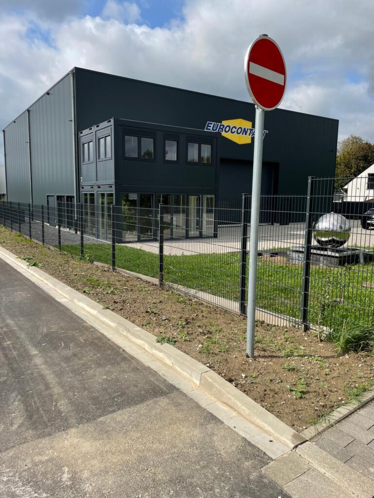 Eine Containeranlage vor einem Gebäude mit dunkelgrauer farbe. Auf dem Container ist der Schriftzug Eurocontain zu lesen.