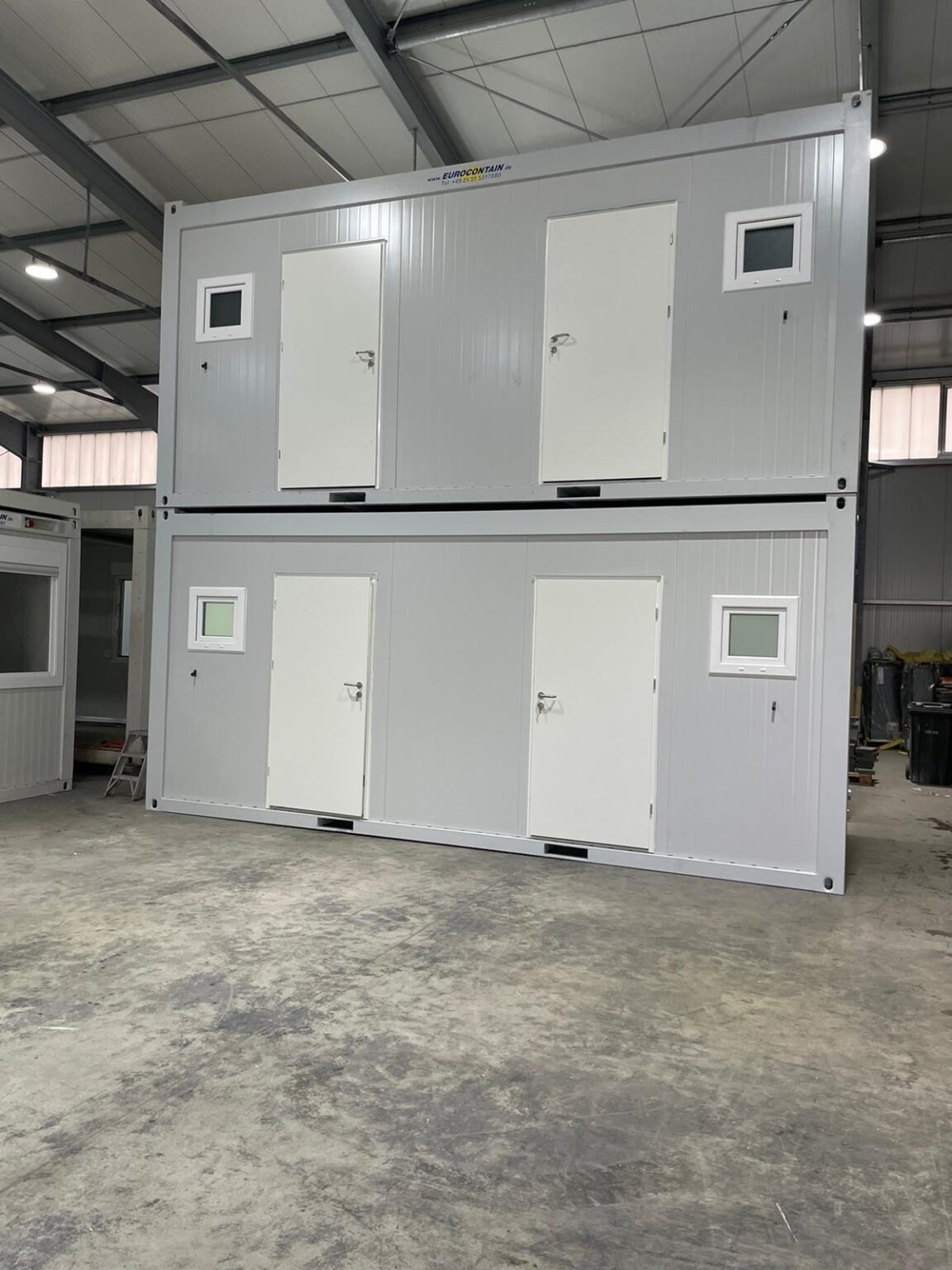Un contenedor EC20-23 - WC D+H 3 con puertas blancas y pequeñas ventanas en la parte delantera.